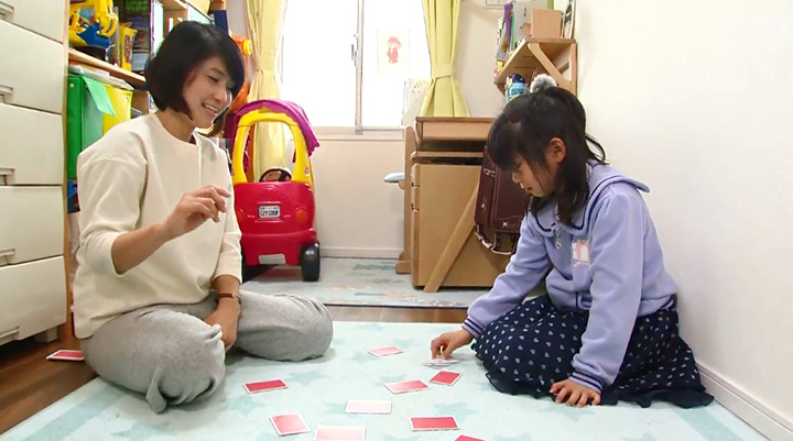 カーペットの上で子供とカードで遊んでいる母親