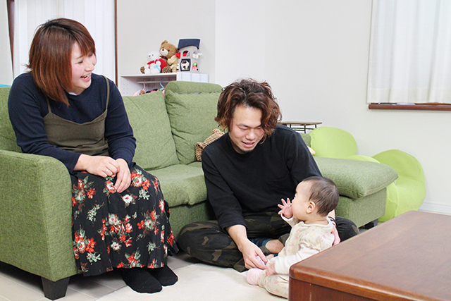 子供と遊んでいる父親と、笑顔で見てる母親